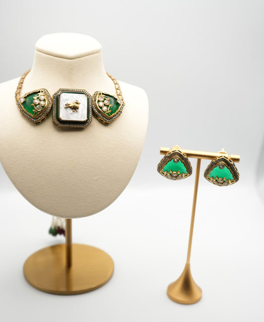 Gold- plated necklace with three gem-studded panels in deep green and white, accented by CZ stones and a bird motif.